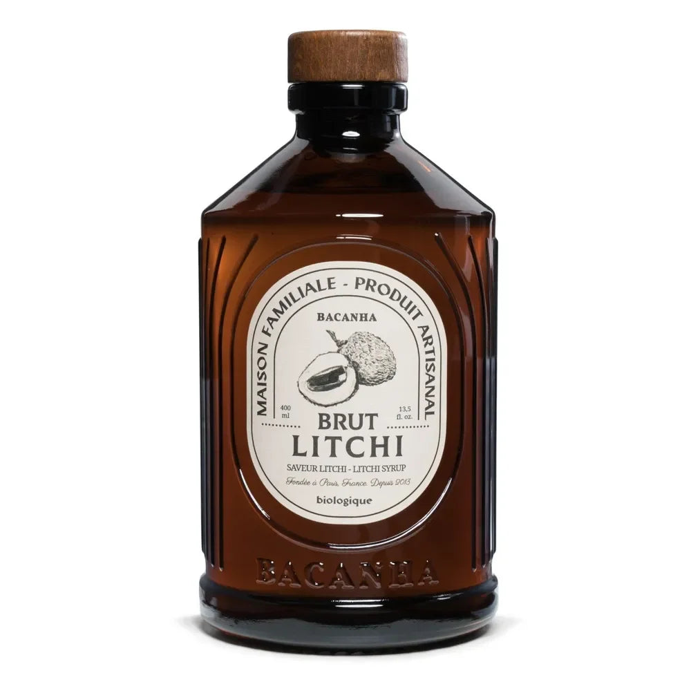 Braunglasflasche mit hellem Bio-Litschisirup und einem dunklen Holzstopfen. Auf dem Etikett steht „Bacanha Sirop de Litchi Bio“.