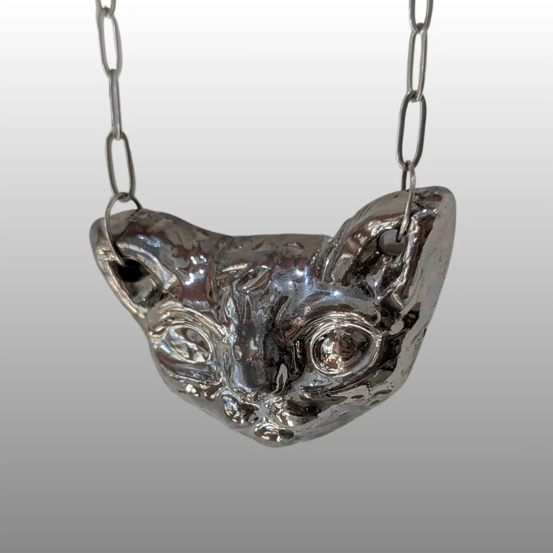 Silberne Halskette mit handgefertigtem, keramischem Anhänger in Form eines stilisierten Sphinxkatzenkopfes, glasiert mit 18k Titanglasur.