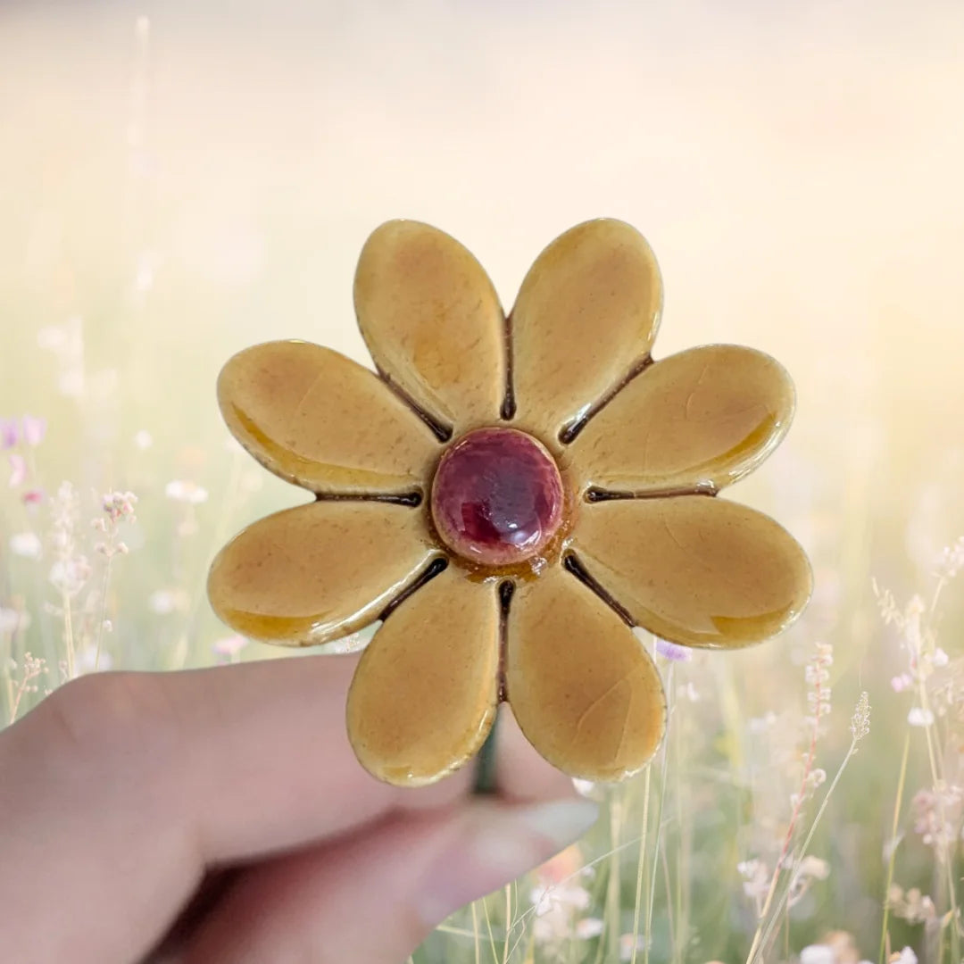 Dunkelgelbes Keramik Gänseblümchen mit einem grünen Metallstiel.