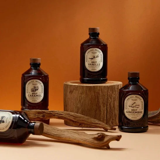 Eine elegante amberfarbene Flasche Bacanha Sirup mit weißem Etikett und stilvollem Design, umgeben von frischen Zutaten.