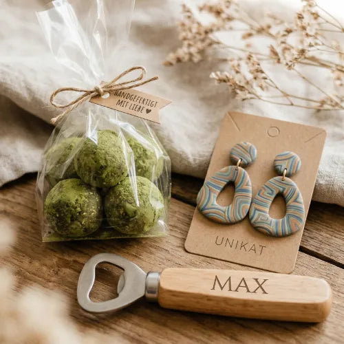 Drei handgemachte Geschenke: Grüne Trüffelpralinen in Zellophan, gemusterte Ohrringe auf Unikat-Pappe, Flaschenöffner mit graviertem 'MAX'