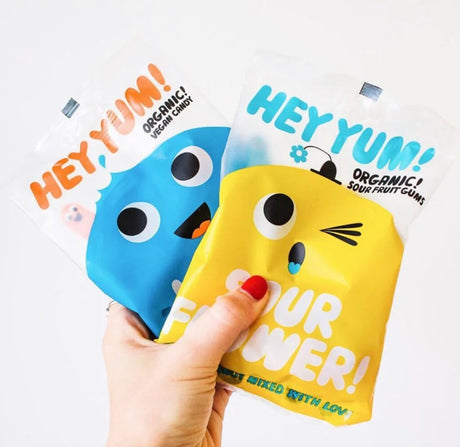 Buntes und verspieltes HEY YUM! Logo mit dem Schriftzug "HEY YUM! Organic Candy" und mehreren bunten Fruchtgummis im Vordergrund.