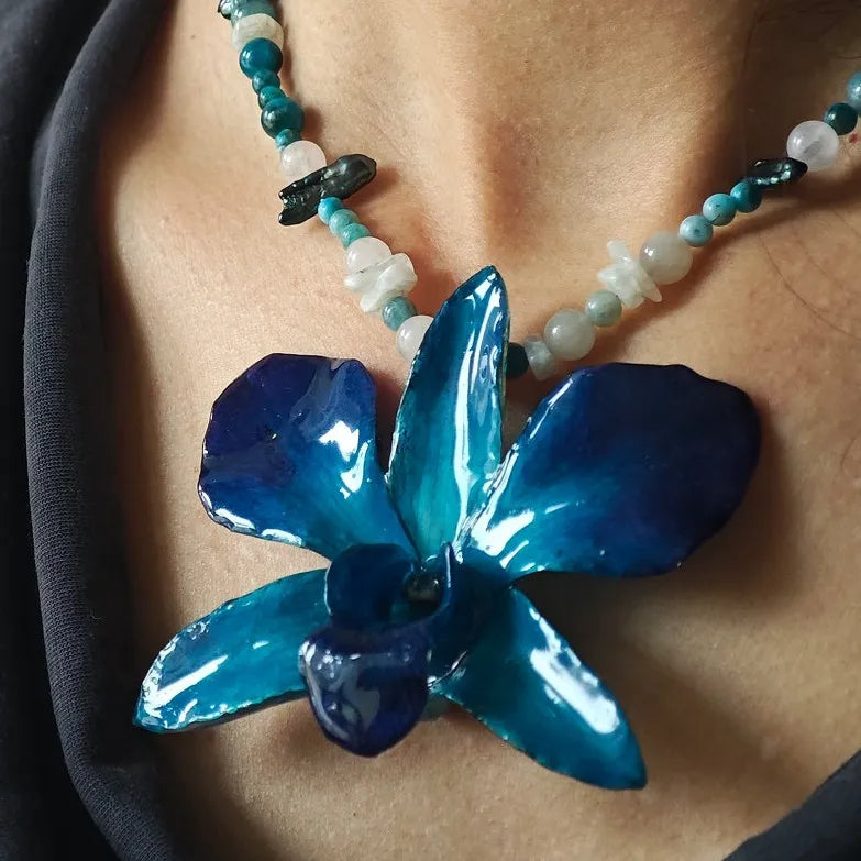Nahaufnahme einer blauen Orchideen-Halskette mit Perlen und Steinen auf der Haut getragen, rechts abgeschnitten