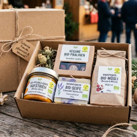 Eine offene Geschenkbox mit veganen Produkten: Bio-Pralinen, Kürbis-Chili-Aufstrich, Lavendel-Rosmarin Bio-Seife und Beeren-Nuss Bio-Müsli