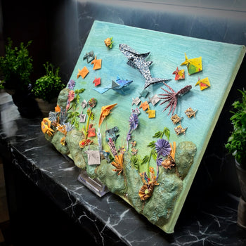 Individuelle Origami-Miniaturwelt von Künstlerhände – Handgefertigte, frei platzierbare Origami-Elemente auf Leinwand oder in einer Holzbox. Einzigartige, personalisierte Kunstwerke für Zuhause oder als Geschenk.