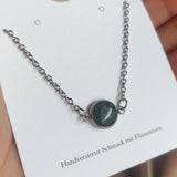 Halskette aus Edelstahl mit einem handgesammelten Flussstein-Anhänger, gefertigt von Steinschmuck Austria. Das Design vereint modernen Edelstahlschmuck mit einem natürlichen Stein, der in der Mitte des Anhängers eingefasst ist. Perfektes Accessoire für Naturverbundene, handgemacht in Österreich.