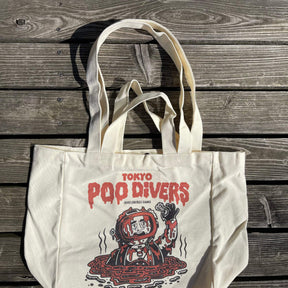 „Tokyo Poo Divers“ Tote Bag von Heldbergs Games, aus 16-Unzen-Baumwolle. Maße 32 x 33 x 16 cm, mit Magnetverschluss und Innentasche. Freches Design für urbane Legenden.