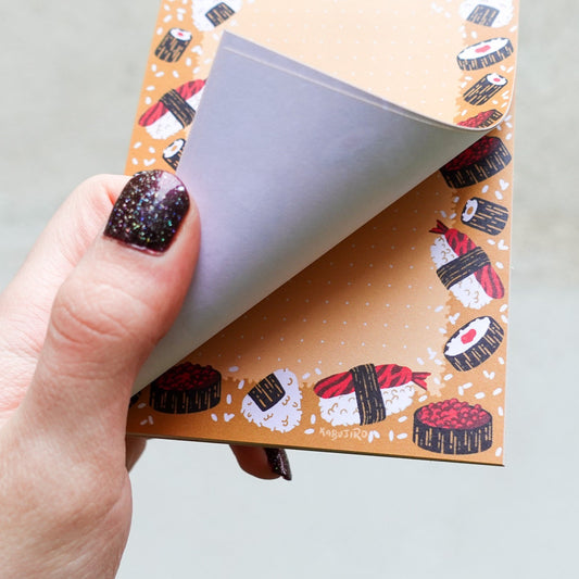 Sushi and Onigiri A6 Notizblock – Niedlicher Notizblock mit Sushi- und Onigiri-Motiven, A6-Format, 50 Seiten, 80gsm Papier. Dreizack Wien.