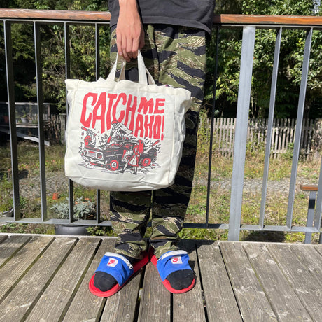 „Catch me Aho“ Tote Bag von Heldbergs Games, inspiriert von Sukeban-Kultur. Hergestellt aus 16-Unzen-Baumwolle, Maße 32 x 33 x 16 cm, mit Magnetverschluss und Innentasche. Frecher Style für Abenteuer.