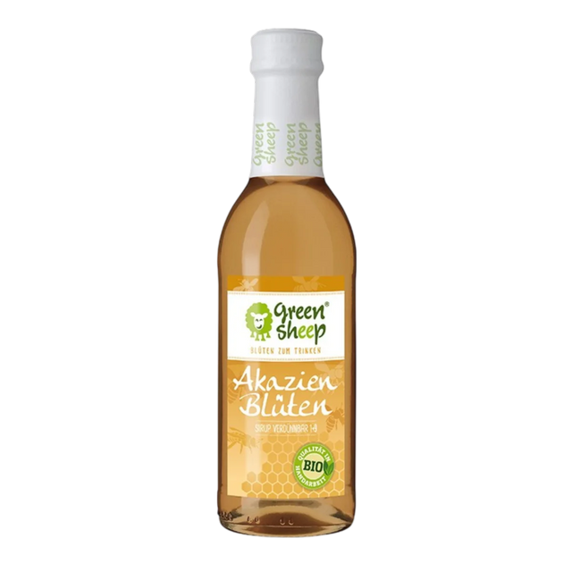Eine Glasflasche mit hellem Akazienblüten Sirup der Marke Green Sheep, umringt von zarten Akazienblüten und Blättern.
