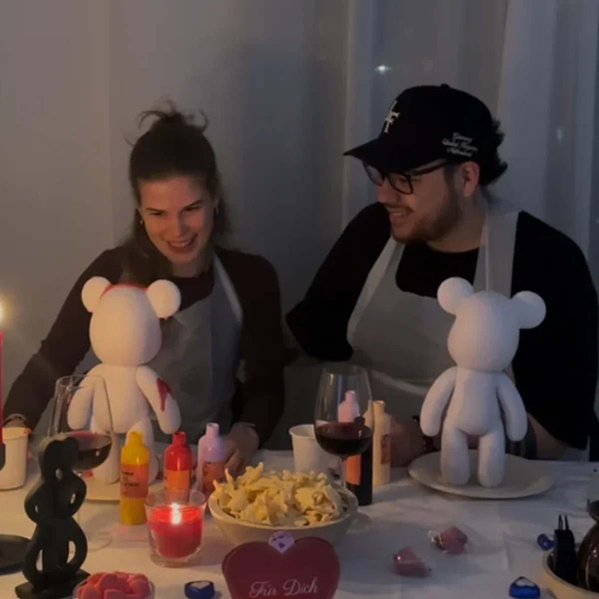 DIY-Set mit weißem Bären zum Bemalen und drei bunten Acrylfarben. Auf einem Tisch mit Arbeitsmaterialien angerichtet.