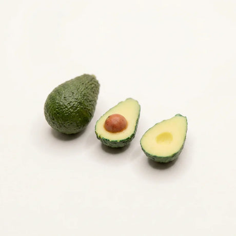 Handmodellierte Avocado-Miniatur in zwei Hälften und ganz, präsentiert in schwarzem Echtholzrahmen 22x22 cm mit Passepartout.