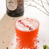 Braunglasflasche mit hellem Bio-Litschisirup und einem dunklen Holzstopfen. Auf dem Etikett steht „Bacanha Sirop de Litchi Bio“.