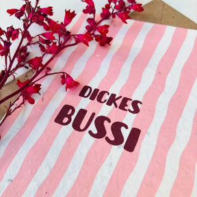 Grußkarte aus beigem Saatpapier mit Aufschrift „Dickes Bussi" und beiliegendem Kuvert.