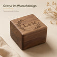 Quadratische Ringbox aus dunklem Walnussholz mit glänzender Oberfläche und schwarzer Samtausstattung im Inneren.