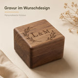 Quadratische Ringbox aus dunklem Walnussholz mit glänzender Oberfläche und schwarzer Samtausstattung im Inneren.
