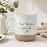 Weiß gesprenkelte Steingut Tasse mit farbig graviertem Wunschdesign und unglasiertem Boden.