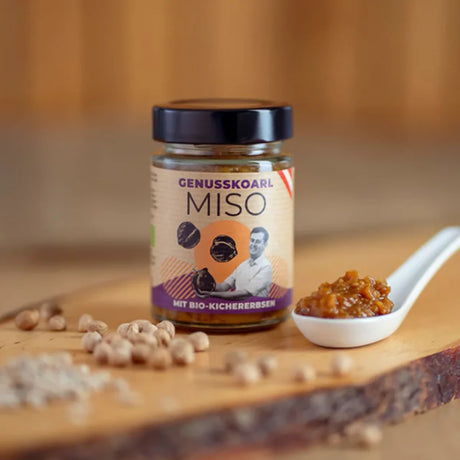 Ein Glas Kichererbsen Miso Bio mit braun-gelblichen, grobstückigen Paste und einem weißen Etikett.