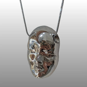 Halskette mit einem ca. 2,5 cm breiten, detailreichen Puppen-Kopf Anhänger aus weißer Keramik mit 18k Platinglasur, an einer 925er Silberkette.