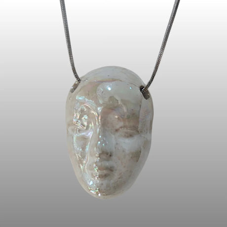 Halskette mit Anhänger in Form eines Puppenkopfes aus Keramik mit Perlmutt-Glasur an einer silbernen Kette.