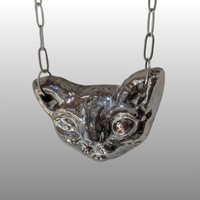 Silberne Halskette mit handgefertigtem, keramischem Anhänger in Form eines stilisierten Sphinxkatzenkopfes, glasiert mit 18k Titanglasur.