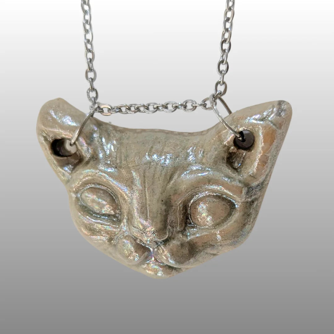 Halskette mit detailreichem Sphinxkatzen-Kopf aus schimmernder Perlmutt-Keramik an einer silbernen Kette.