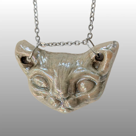 Halskette mit detailreichem Sphinxkatzen-Kopf aus schimmernder Perlmutt-Keramik an einer silbernen Kette.