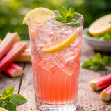 Glasflasche mit Rhabarber Mix-Saft von Green Sheep, daneben ein Glas Rhabarber-Limo mit Eis und Minze.