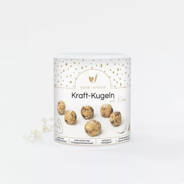 Weiße Schale mit Kraft-Kugeln mit Kokos und Vitamin B-Komplex auf hellem Hintergrund, bereit zum Verzehr.
