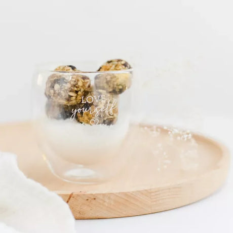 Weiße Schale mit Kraft-Kugeln mit Kokos und Vitamin B-Komplex auf hellem Hintergrund, bereit zum Verzehr.