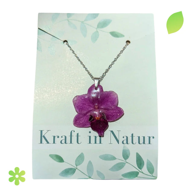 Halskette mit einer echten, lilafarbenen Orchideenblüte, eingebettet in transparentes Kunstharz, an einer silbernen Kette.