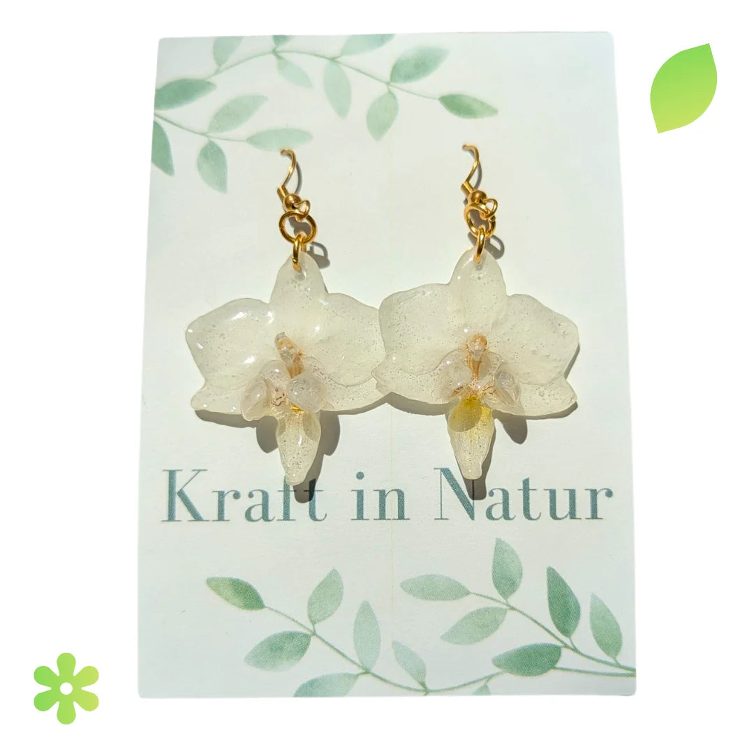Paar Ohrringe mit einer echten, rosa-lila Orchideenblüte, die in transparentem Resin eingegossen ist.
