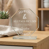 Ein achteckiger Pokal aus klarem Kristallglas auf einem flachen Sockel mit weißer Gravur
