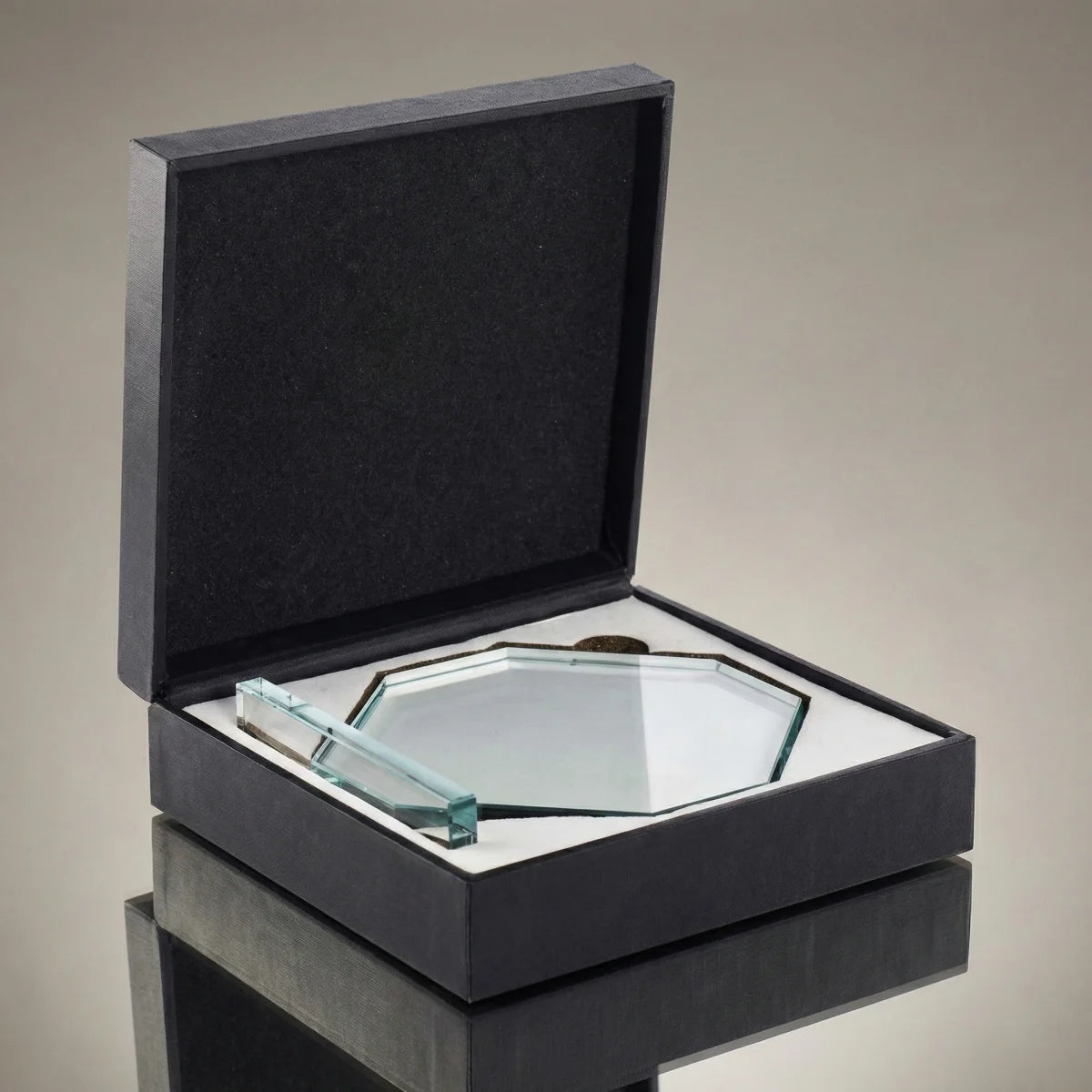 Ein achteckiger Pokal aus klarem Kristallglas auf einem flachen Sockel mit weißer Gravur