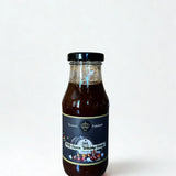 Eine Glasflasche mit dunkler, sämiger BBQ Sauce „Smoky Bourbon Honey“ von Kronenfeinkost.
