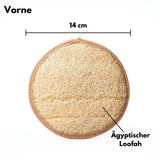 Ein rundes, beiges Loofah Körperpad mit einer Schlaufe auf einer hellen Oberfläche