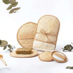 Ein Set aus vier hellen Luffa-Pflegeprodukten inklusive Handschuh und runden Pads auf einem Holzuntergrund.