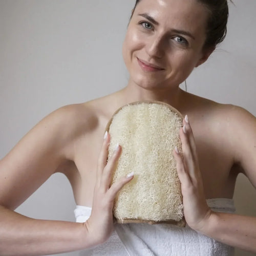 Ein rechteckiger Luffa Peelinghandschuh mit heller Baumwollseite und strukturierter Oberfläche aus Luffa-Fasern.