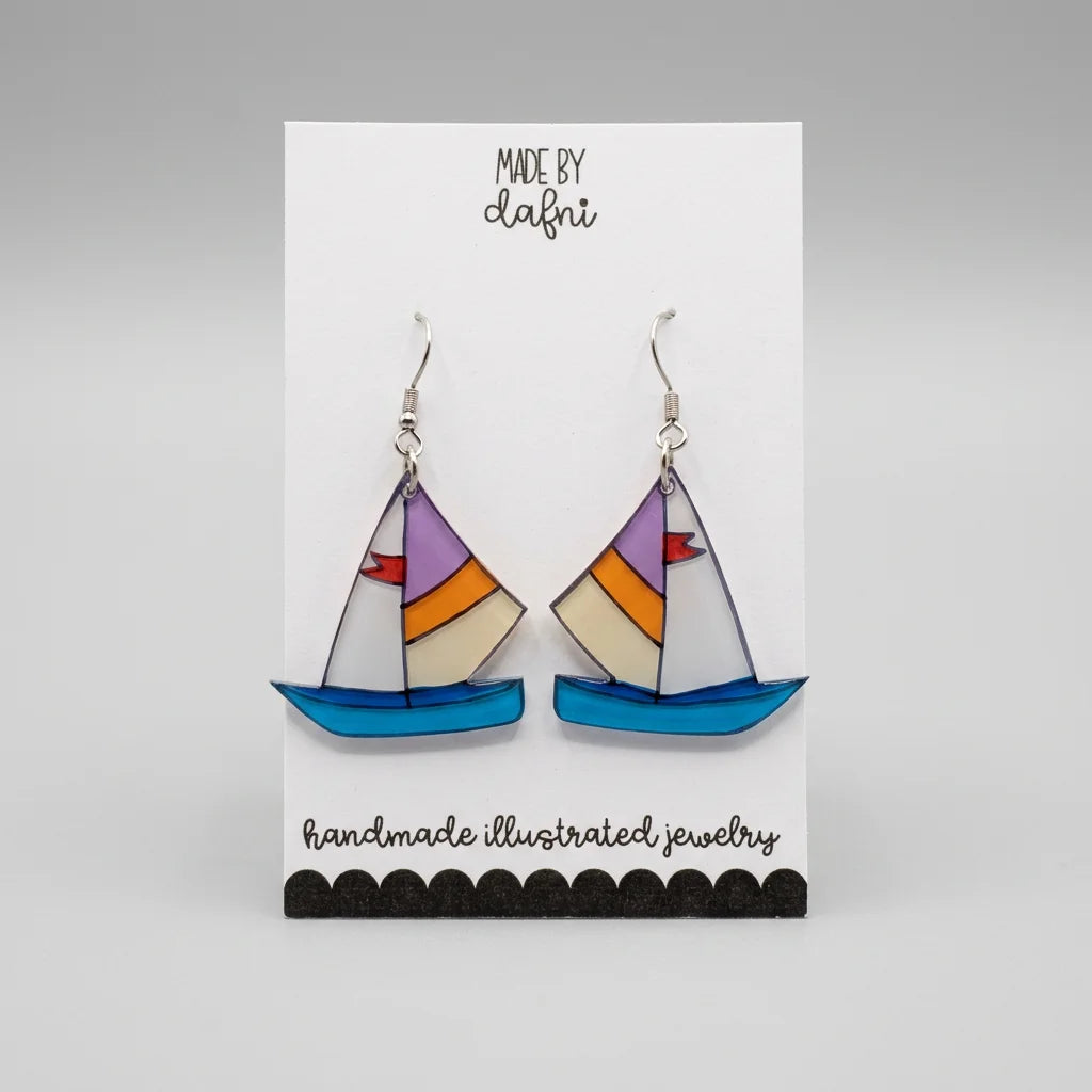 Ohrringe aus Plexiglas mit handillustriertem Segelboot-Motiv in Blau, Orange und Lila an silberfarbenen Edelstahl-Haken, Anhänger ca. 3 cm groß.
