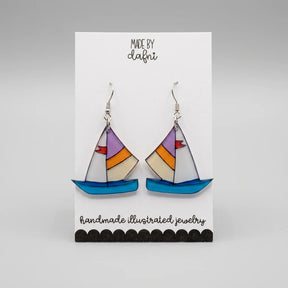 Ohrringe aus Plexiglas mit handillustriertem Segelboot-Motiv in Blau, Orange und Lila an silberfarbenen Edelstahl-Haken, Anhänger ca. 3 cm groß.