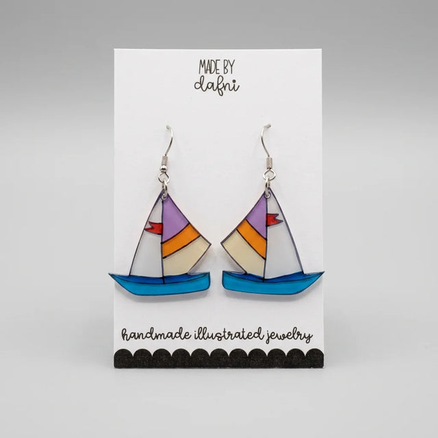 Ohrringe aus Plexiglas mit handillustriertem Segelboot-Motiv in Blau, Orange und Lila an silberfarbenen Edelstahl-Haken, Anhänger ca. 3 cm groß.