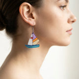 Ohrringe aus Plexiglas mit handillustriertem Segelboot-Motiv in Blau, Orange und Lila an silberfarbenen Edelstahl-Haken, Anhänger ca. 3 cm groß.