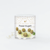 Drei grüne Matcha Power-Kugeln liegen dekorativ neben einer kleinen Schale mit Teepulver.