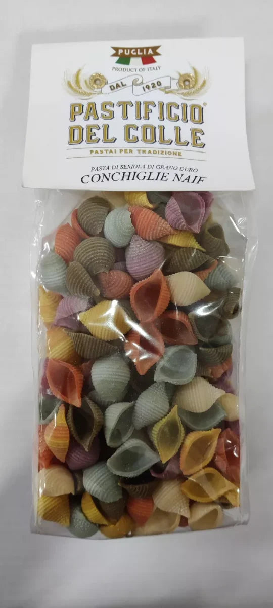 Bunte, handgemachte Naif Conchiglie Nudeln in Muschelform, liegend auf einer rustikalen Oberfläche