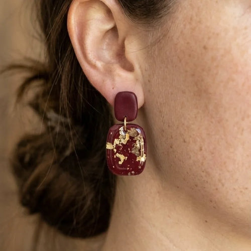 Dunkelrote Ohrringe aus Polymer Clay mit eingearbeiteten Goldflocken und Weinstein-Kristallen auf hellem Hintergrund