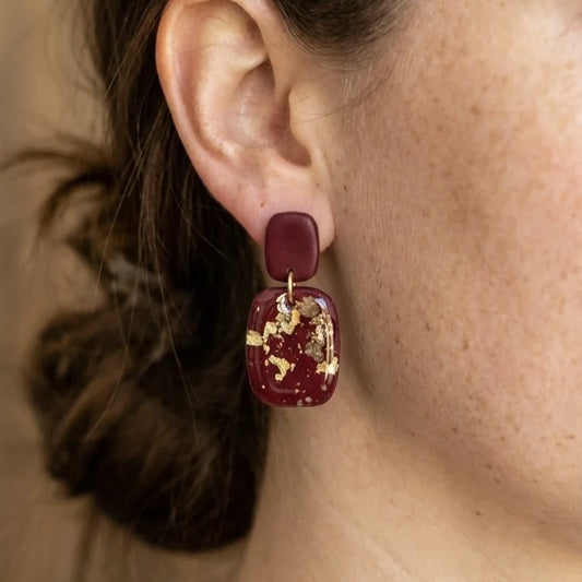 Dunkelrote Ohrringe aus Polymer Clay mit eingearbeiteten Goldflocken und Weinstein-Kristallen auf hellem Hintergrund