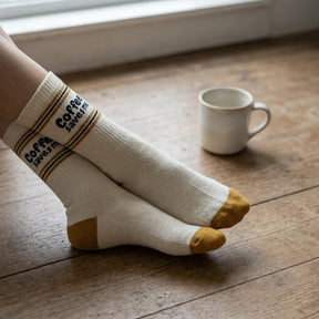 Beige-braune Sportsocken aus Baumwolle mit aufgedrucktem Spruch „coffee saves me" und gepolsterter Sohle.