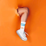 Blaue und orange Sportsocken aus Baumwolle mit aufgedrucktem Spruch „Good Vibes" auf weißem Hintergrund.