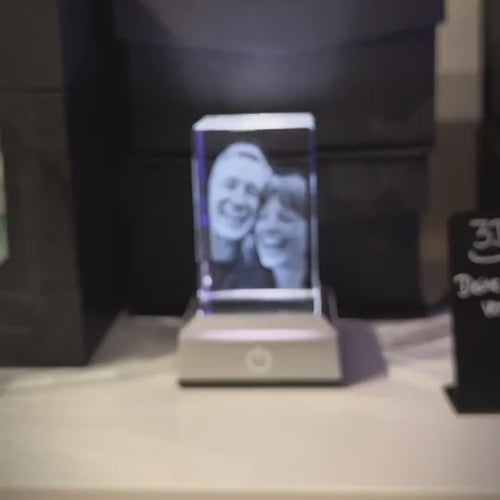 2.5D Kristall-Relief einer glücklichen Frau: Detailreiche Portrait-Gravur in einem K9 Kristallglasblock mit plastischer Tiefe, handgefertigt bei Dreizack Wien.