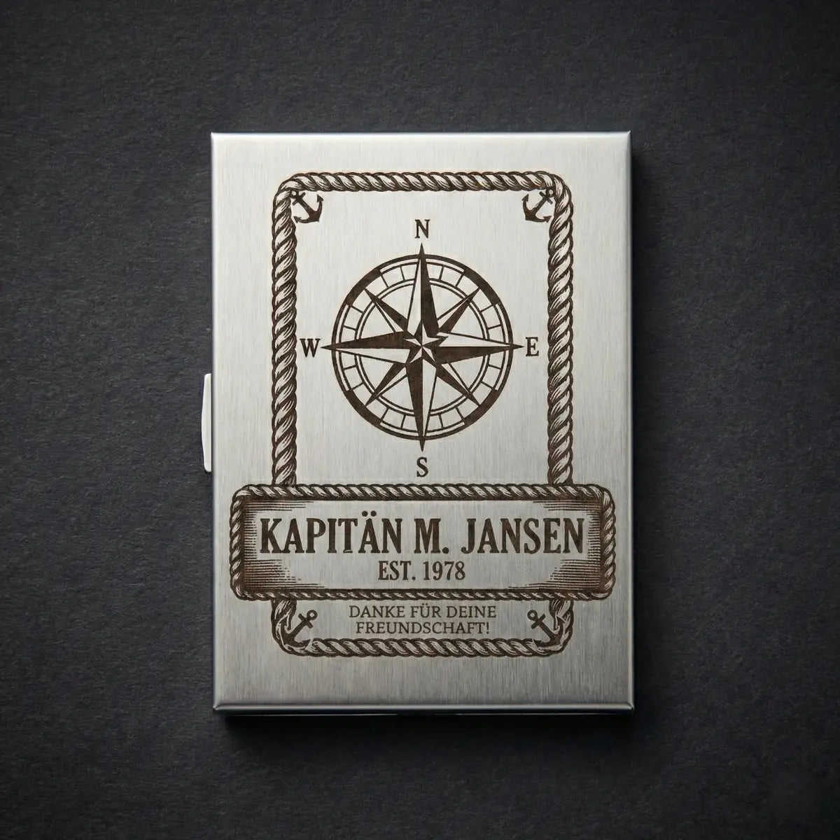 Ein schlankes, silberglänzendes Zigarettenetui aus Edelstahl mit einer individuellen Gravur auf der Vorderseite.